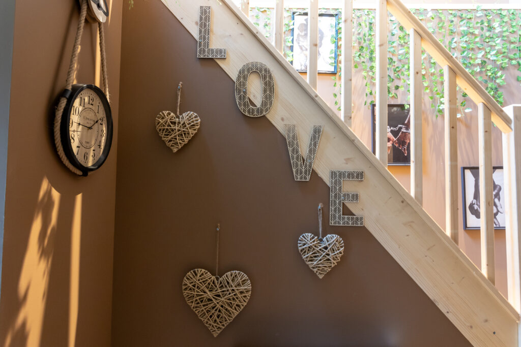 escalier avec des coeurs accrochés en décoration, LOVE, horloge sur la gauche, cadre en arrière plan et décoration murale